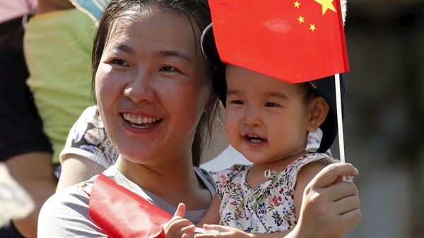 Женщина с ребенком в ожидании выступлений военных вертолетов и самолетов во время парада в честь 70-летия победы во Второй мировой войне в Пекине - Sputnik International