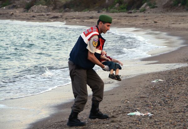A paramilitary police officer carries the lifeless body of an unidentified migrant child, lifting it from the sea shore, near the Turkish resort of Bodrum, Turkey, early Wednesday, Sept. 2, 2015. A paramilitary police officer carries the lifeless body of an unidentified migrant child, lifting it from the sea shore, near the Turkish resort of Bodrum, Turkey, early Wednesday, Sept. 2, 2015. - Sputnik International