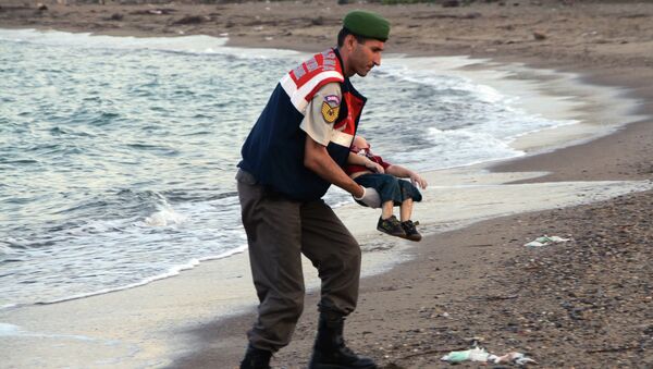 A paramilitary police officer carries the lifeless body of an unidentified migrant child, lifting it from the sea shore, near the Turkish resort of Bodrum, Turkey, early Wednesday, Sept. 2, 2015. - Sputnik International