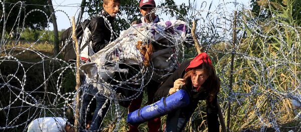 Syrian migrants cross under a fence as they enter Hungary at the border with Serbia, near Roszke, August 27, 2015 - Sputnik International