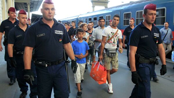 Hungarian police officers guard refugees to a regional train supposed to carry them to a nearby interim camp at a railways station in Budapest, Hungary September 2, 2015 - Sputnik International