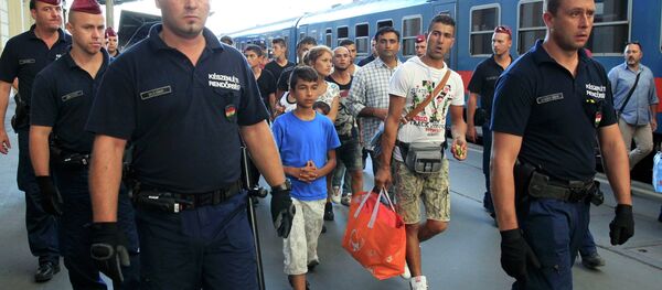 Hungarian police officers guard refugees to a regional train supposed to carry them to a nearby interim camp at a railways station in Budapest, Hungary September 2, 2015 Hungarian police officers guard refugees to a regional train supposed to carry them to a nearby interim camp at a railways station in Budapest, Hungary September 2, 2015 - Sputnik International