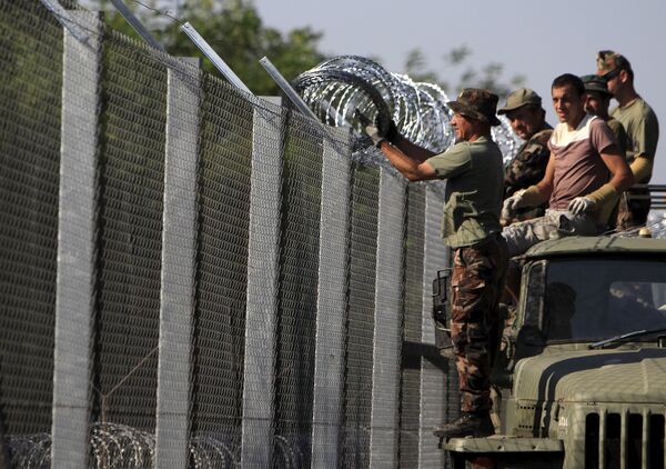 Hungarian soldiers adjust the razor wire on a fence near the town of Asotthalom, Hungary, August 30, 2015 Hungarian soldiers adjust the razor wire on a fence near the town of Asotthalom, Hungary, August 30, 2015 - Sputnik International