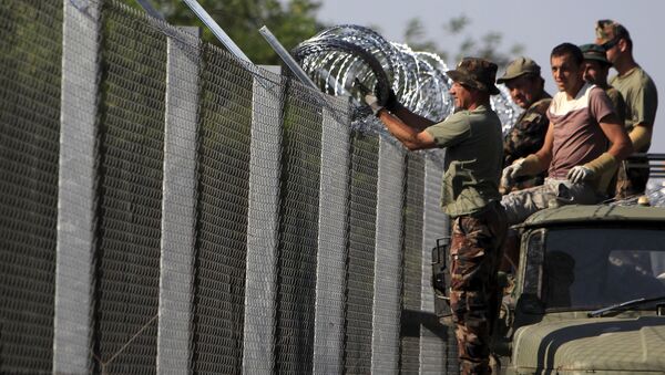 Hungarian soldiers adjust the razor wire on a fence near the town of Asotthalom, Hungary, August 30, 2015 - Sputnik International
