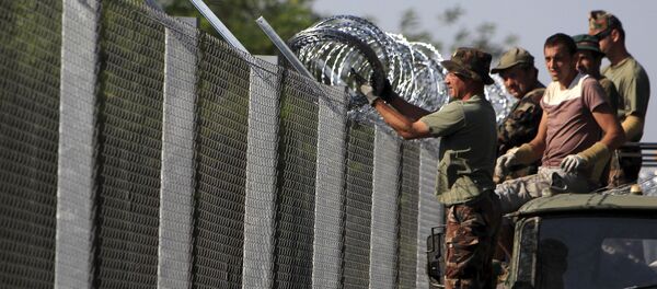 Hungarian soldiers adjust the razor wire on a fence near the town of Asotthalom, Hungary, August 30, 2015 - Sputnik International