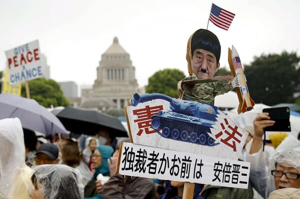 A protester holds a caricature cut-out of Japan's Prime Minister Shinzo Abe during a mass rally against his security bill outside the parliament in Tokyo August 30, 2015 A protester holds a caricature cut-out of Japan's Prime Minister Shinzo Abe during a mass rally against his security bill outside the parliament in Tokyo August 30, 2015 - Sputnik International