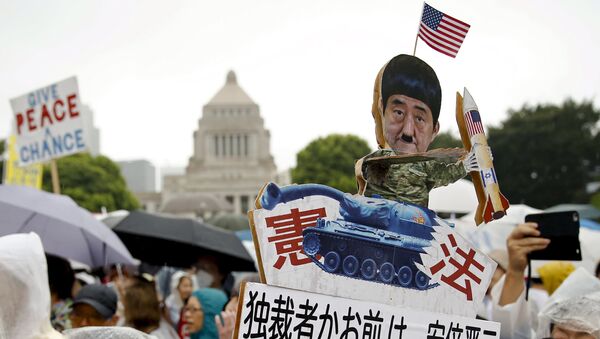 A protester holds a caricature cut-out of Japan's Prime Minister Shinzo Abe during a mass rally against his security bill outside the parliament in Tokyo August 30, 2015 - Sputnik International