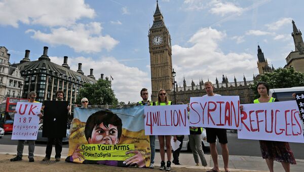 Protestors hold banners during an Amnesty International protest in Parliament Square to urge the British government to do more to help Syrian refugees, London, Saturday, July 11, 2015. - Sputnik International