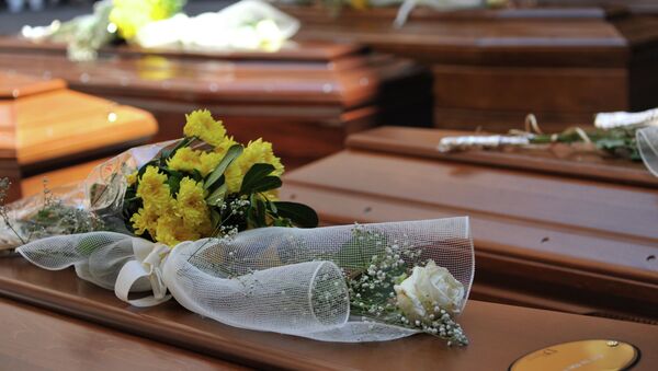 Flowers lay on top of coffins with the remains of 13 migrants who were among up to 800 people who died in a shipwreck in April, in Catania, Sicily, Italy, Tuesday, July 7, 2015 - Sputnik International