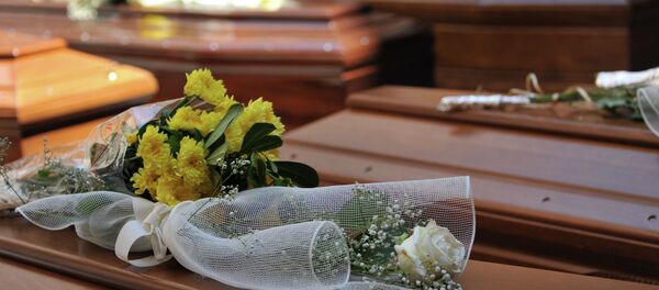 Flowers lay on top of coffins with the remains of 13 migrants who were among up to 800 people who died in a shipwreck in April, in Catania, Sicily, Italy, Tuesday, July 7, 2015 - Sputnik International
