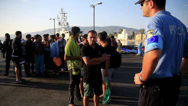 A migrant waits in line next to a Frontex officer (R) at the port of Kos, following a rescue operation off the Greek island of Kos, August 14, 2015 - Sputnik International