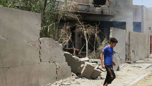 Abdullah Ahmed walks outside his home that was damaged in a bombing in Fallujah, Iraq. The U.S. and its coalition allies have carried out more than 1,000 strikes in Iraq since its campaign began in August - as well as hundreds more by American and Arab air forces in neighboring Syria. - Sputnik International