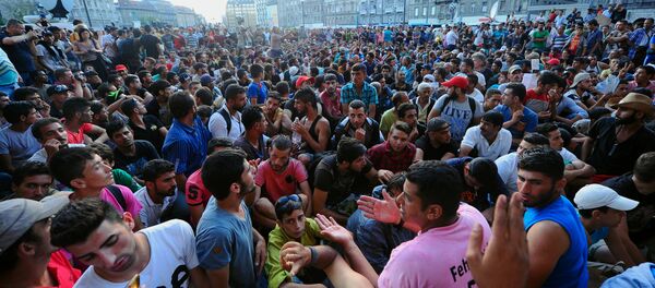 Migrants sit in front of the Keleti (East) railway station in Budapest on September 2, 2015 - Sputnik International