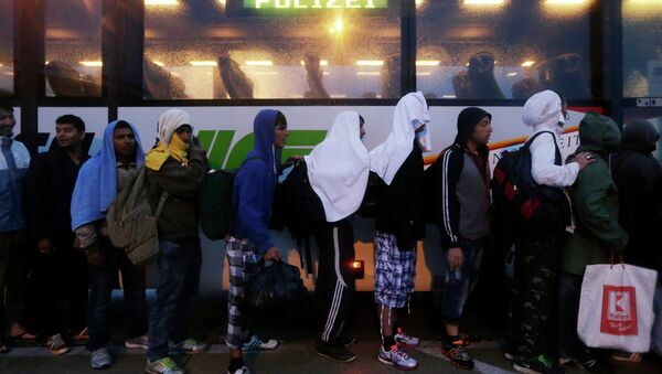 Migrants line up in front of a police bus at the Hungarian-Austrian border in Nickelsdorf, Austria, Saturday, Sept. 5, 2015, where they arrived from Budapest as Austria in the early-morning hours said it and Germany would let them in - Sputnik International