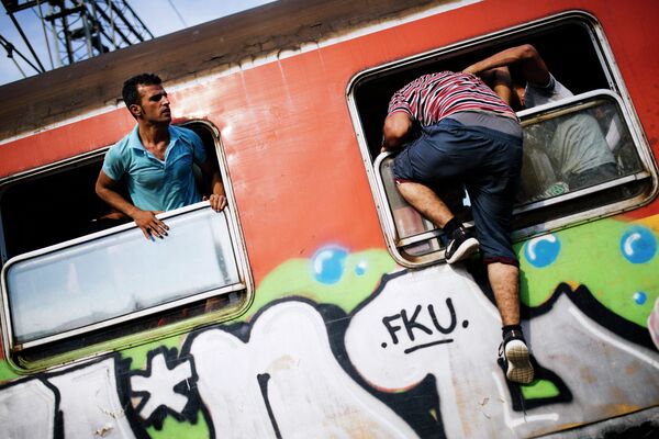 A migrant climbs through a window onto a train heading to the border with Serbia at the train station of Gevgelija, on the Macedonian-Greek border, on August 6, 2015 - Sputnik International