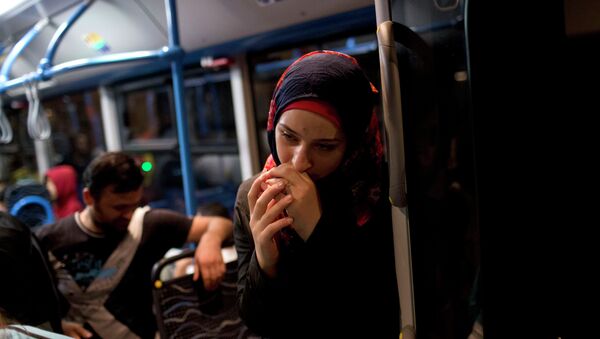 A woman pauses on a bus provided by Hungarian authorities for migrants and refugees at Keleti train station in Budapest, Hungary, Saturday, Sept. 5, 2015 - Sputnik International