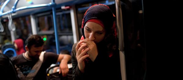 A woman pauses on a bus provided by Hungarian authorities for migrants and refugees at Keleti train station in Budapest, Hungary, Saturday, Sept. 5, 2015 A woman pauses on a bus provided by Hungarian authorities for migrants and refugees at Keleti train station in Budapest, Hungary, Saturday, Sept. 5, 2015 - Sputnik International