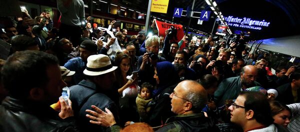 Wellwishers surround a family of migrants from Syria (at C, man in hat and woman with baby) arriving with a train from Vienna at the railway station in Frankfurt, Germany, September 5, 2015 - Sputnik International