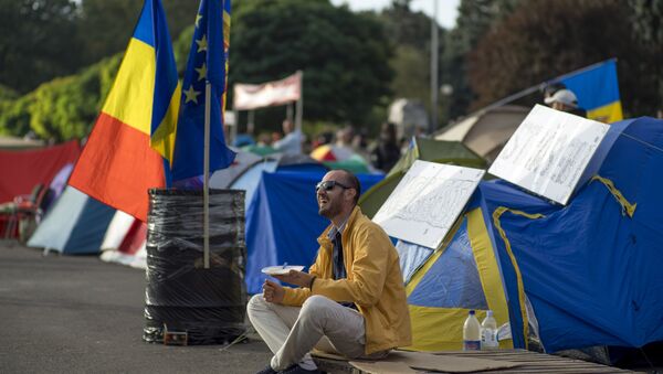 A demonstrator has breakfast as he sits next to tents set up by protesters in central Chisinau on September 7, 2015 after an anti-government rally. - Sputnik International