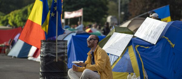 A demonstrator has breakfast as he sits next to tents set up by protesters in central Chisinau on September 7, 2015 after an anti-government rally. A demonstrator has breakfast as he sits next to tents set up by protesters in central Chisinau on September 7, 2015 after an anti-government rally. - Sputnik International