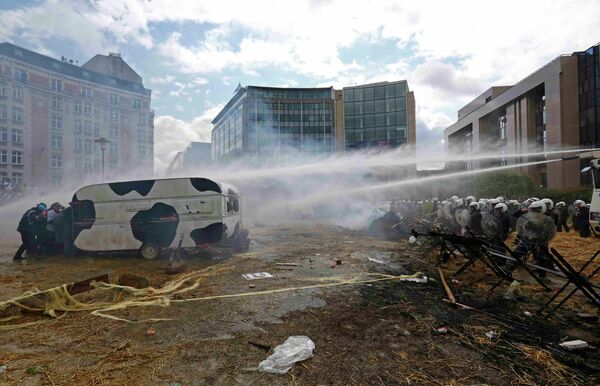 Protesters shelter behind a caravan as Belgian riot police uses water canons - Sputnik International