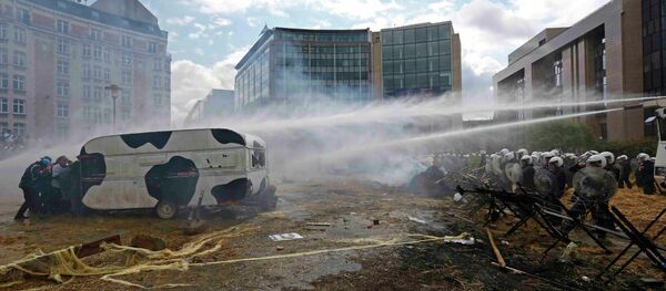 Protesters shelter behind a caravan as Belgian riot police uses water canons Protesters shelter behind a caravan as Belgian riot police uses water canons - Sputnik International