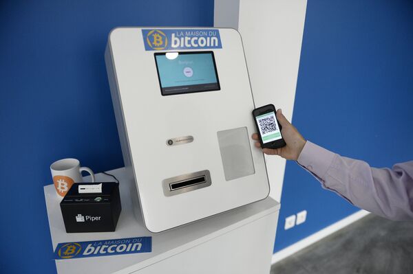 This picture taken on June 20, 2014, shows a man placing his phone next to a Bitcoins (virtual currency) dispenser at La Maison du Bitcoin in Paris. This picture taken on June 20, 2014, shows a man placing his phone next to a Bitcoins (virtual currency) dispenser at La Maison du Bitcoin in Paris. - Sputnik International
