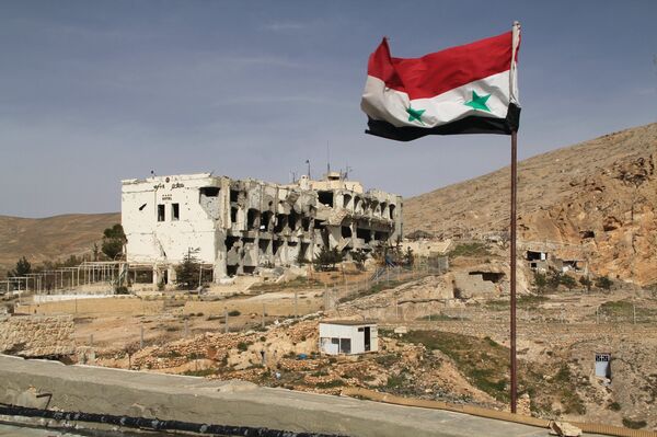 A Syrian flag on the background of ruined houses in the Syrian town of Maaloula, 55 km from Damascus, which was twice captured and looted by Jabhat al-Nusra militants. - Sputnik International
