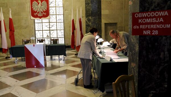 A woman takes her ballot paper during a referendum asking people to vote on changing the voting system, the funding of political parties and taxation rules, in Warsaw, Poland, September 6, 2015. - Sputnik International