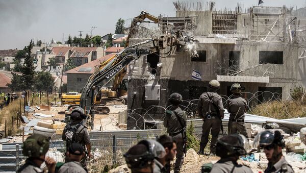 Israeli officers from the Border Patrol watch over the demolition of a building at the Jewish settlement of Beit El, near the West Bank town of Ramallah, Wednesday, July 29, 2015. - Sputnik International
