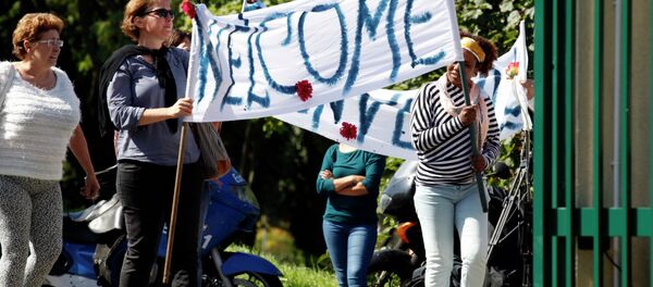 Neighbours hold a banner to cheer a group of migrants. Neighbours hold a banner to cheer a group of migrants. - Sputnik International
