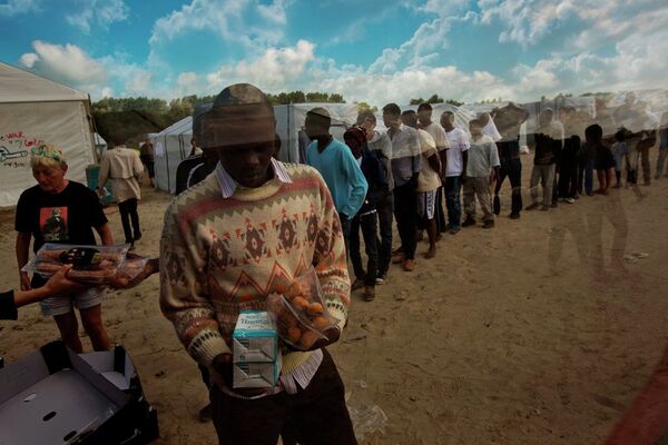 In this Tuesday, Aug. 4, 2015 file photo, migrants receive their food rations distributed by the Banque Alimentaire of Calais at a camp set in northern France. In this Tuesday, Aug. 4, 2015 file photo, migrants receive their food rations distributed by the Banque Alimentaire of Calais at a camp set in northern France. - Sputnik International