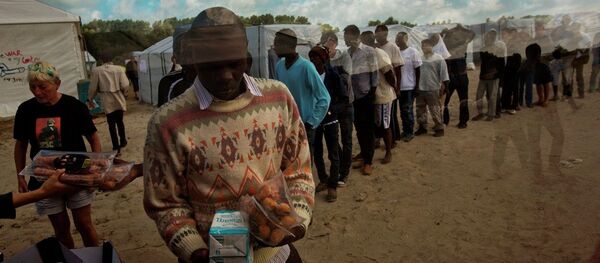 In this Tuesday, Aug. 4, 2015 file photo, migrants receive their food rations distributed by the Banque Alimentaire of Calais at a camp set in northern France. In this Tuesday, Aug. 4, 2015 file photo, migrants receive their food rations distributed by the Banque Alimentaire of Calais at a camp set in northern France. - Sputnik International