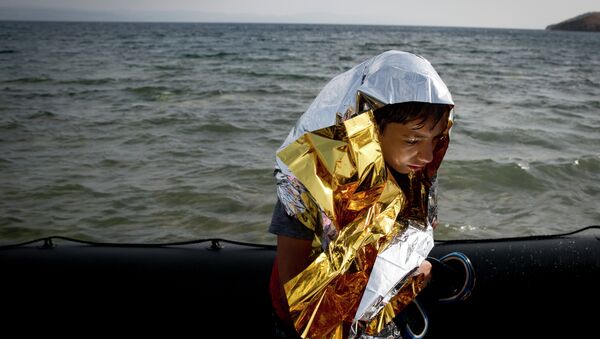 A young Syrian boy is wrapped with a thermal blanket as he arrives with others at the coast on a dinghy after crossing from Turkey, at the island of Lesbos, Greece, Monday, Sept. 7, 2015. - Sputnik International