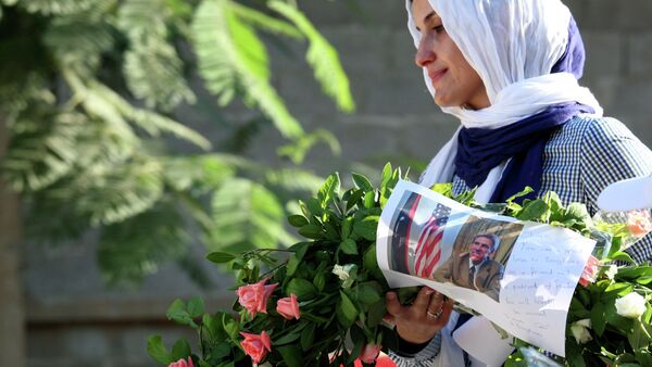 Libyan woman carries a wreath with a photo of U.S. Ambassador Chris Stevens on it as she and others gather to pay their respect to the victims of the Tuesday, Sept. 11, 2012 attack on the U.S. consulate, in Benghazi, Libya, Monday, Sept. 17, 2012 - Sputnik International