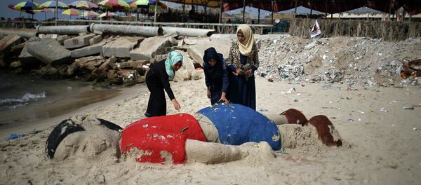 Palestinian girls put flowers on a sand sculpture by Indian artist Sudarsan Pattnaik depicting Syrian boy Aylan Kurdi, a three-year-old boy who drowned off Turkey, on September 7, 2015, on Gaza city beach - Sputnik International