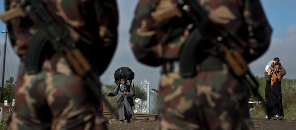 Hungarian army officers stand at the Serbian-Hungarian border as a Syrian refugee women crosses, near Roszke, southern Hungary, Saturday, Sept. 12, 2015 Hungarian army officers stand at the Serbian-Hungarian border as a Syrian refugee women crosses, near Roszke, southern Hungary, Saturday, Sept. 12, 2015 - Sputnik International