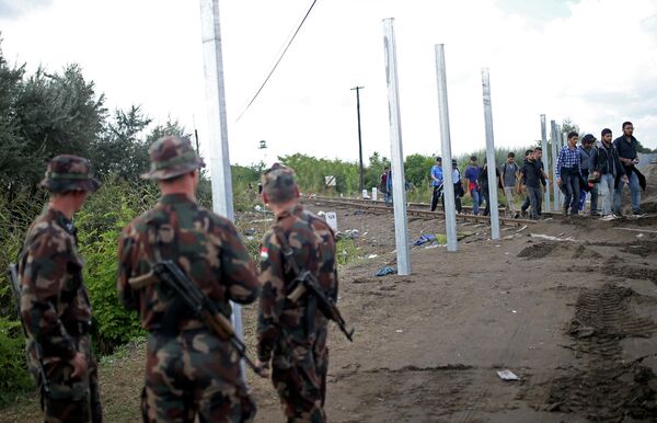 Hungarian soldiers stand guard as migrants cross at the border near Roszke, Hungary September 12, 2015 Hungarian soldiers stand guard as migrants cross at the border near Roszke, Hungary September 12, 2015 - Sputnik International