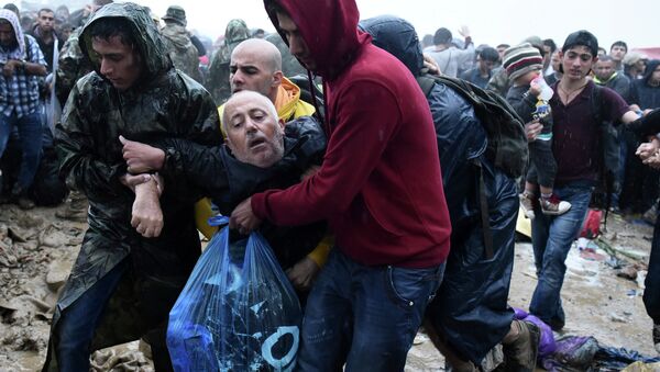 Migrants help an elderly man to pass from the northern Greek village of Idomeni to southern Macedonia, Thursday, Sept. 10, 2015. Thousands of people, including many families with young children, braved torrential downpours to cross Greeceís northern border with Macedonia early Thursday, after Greek authorities managed to register about 17,000 people on the island of Lesbos in the space of a few days, allowing them to continue their journey north into Europe. - Sputnik International