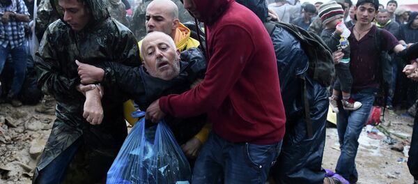 Migrants help an elderly man to pass from the northern Greek village of Idomeni to southern Macedonia, Thursday, Sept. 10, 2015. Thousands of people, including many families with young children, braved torrential downpours to cross Greeceís northern border with Macedonia early Thursday, after Greek authorities managed to register about 17,000 people on the island of Lesbos in the space of a few days, allowing them to continue their journey north into Europe. Migrants help an elderly man to pass from the northern Greek village of Idomeni to southern Macedonia, Thursday, Sept. 10, 2015. Thousands of people, including many families with young children, braved torrential downpours to cross Greeceís northern border with Macedonia early Thursday, after Greek authorities managed to register about 17,000 people on the island of Lesbos in the space of a few days, allowing them to continue their journey north into Europe. - Sputnik International