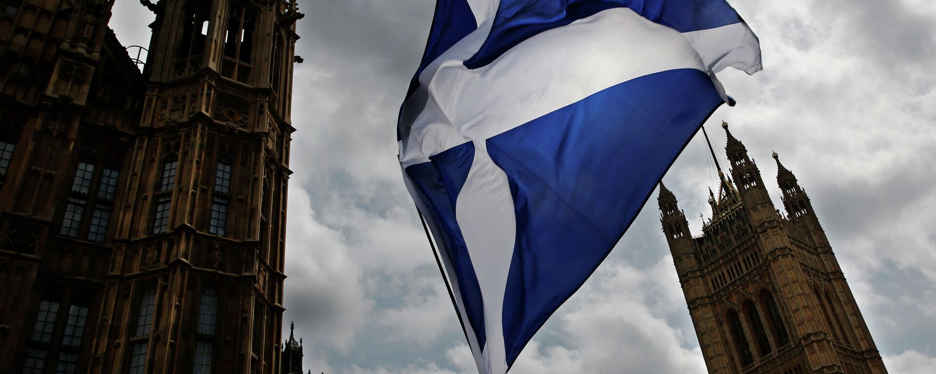 A member of public flies a giant Scottish Saltire flag outside the Houses of Parliament shortly before Scotland First Minister Nicola Sturgeon posed with newly-elected Scottish National Party (SNP) MPs during a photocall in London on May 11, 2015 - Sputnik International, 1920, 30.11.2020