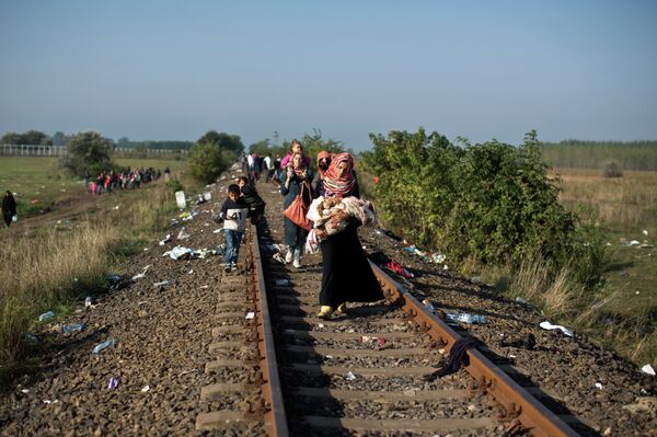 Syrian women carrying their children make their way along a railway track after crossing the Serbian-Hungarian border near Roszke, southern Hungary, Sunday, Sept. 13, 2015 Syrian women carrying their children make their way along a railway track after crossing the Serbian-Hungarian border near Roszke, southern Hungary, Sunday, Sept. 13, 2015 - Sputnik International