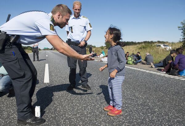 Danish policeman plays with a migrant girl at the E45 freeway north of Padborg September 9, 2015 Danish policeman plays with a migrant girl at the E45 freeway north of Padborg September 9, 2015 - Sputnik International