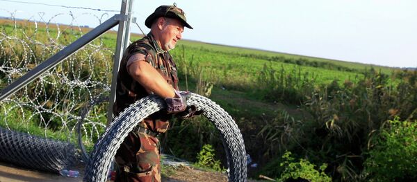 Hungarian soldier carries barbed wire for a fence under construction along the border with Serbia near the migrant collection point in Roszke, Hungary, September 14, 2015 Hungarian soldier carries barbed wire for a fence under construction along the border with Serbia near the migrant collection point in Roszke, Hungary, September 14, 2015 - Sputnik International