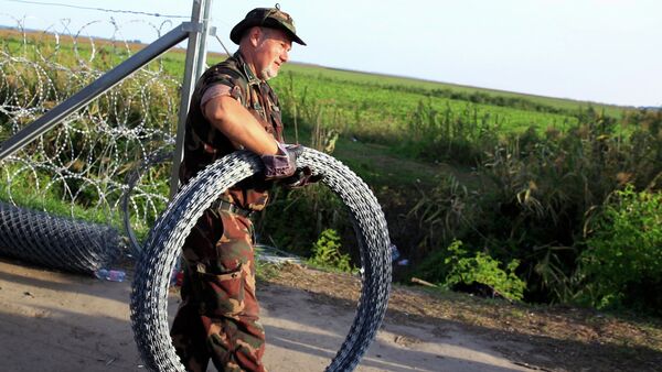 Hungarian soldier carries barbed wire for a fence under construction along the border with Serbia near the migrant collection point in Roszke, Hungary, September 14, 2015 - Sputnik International
