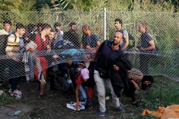 Migrants pass under a highway security fence as they try to find a new way to enter Hungary after Hungarian police sealed the border with Serbia near the village of Horgos, Serbia, September 14, 2015 Migrants pass under a highway security fence as they try to find a new way to enter Hungary after Hungarian police sealed the border with Serbia near the village of Horgos, Serbia, September 14, 2015 - Sputnik International