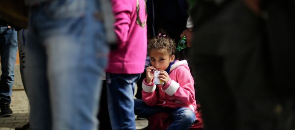 A girl drinks some juice after she arrived with other refugees at the train station of the southern German border town Passau, Tuesday, Sept. 15, 2015. - Sputnik International