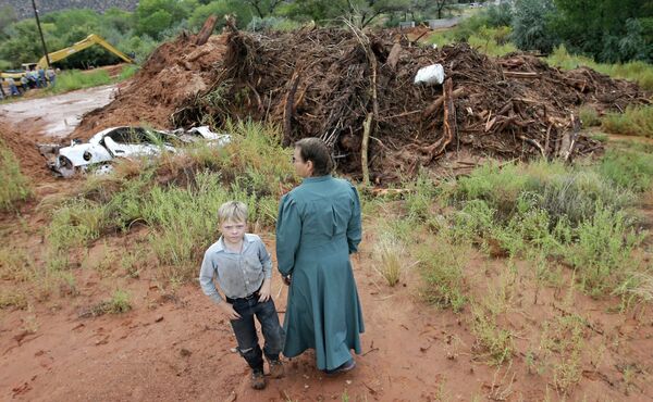 People look over debris and the remains of a car following a flash flood Tuesday. People look over debris and the remains of a car following a flash flood Tuesday. - Sputnik International
