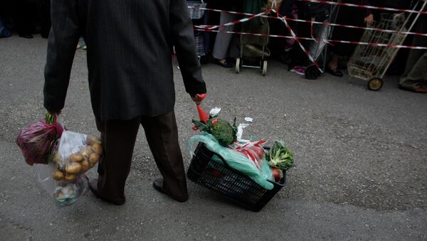 A man pulls a crate of vegetables he has got for free from protesting farmers' market vendors. - Sputnik International