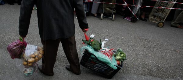 A man pulls a crate of vegetables he has got for free from protesting farmers' market vendors. - Sputnik International